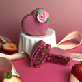 Heart-shaped purple cookie with a pink rose on top, cut open to reveal a filling, on a pink background.