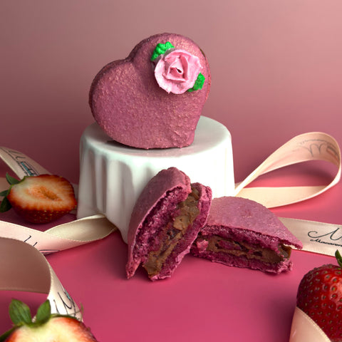 Heart-shaped purple cookie with a pink rose on top, cut open to reveal a filling, on a pink background.
